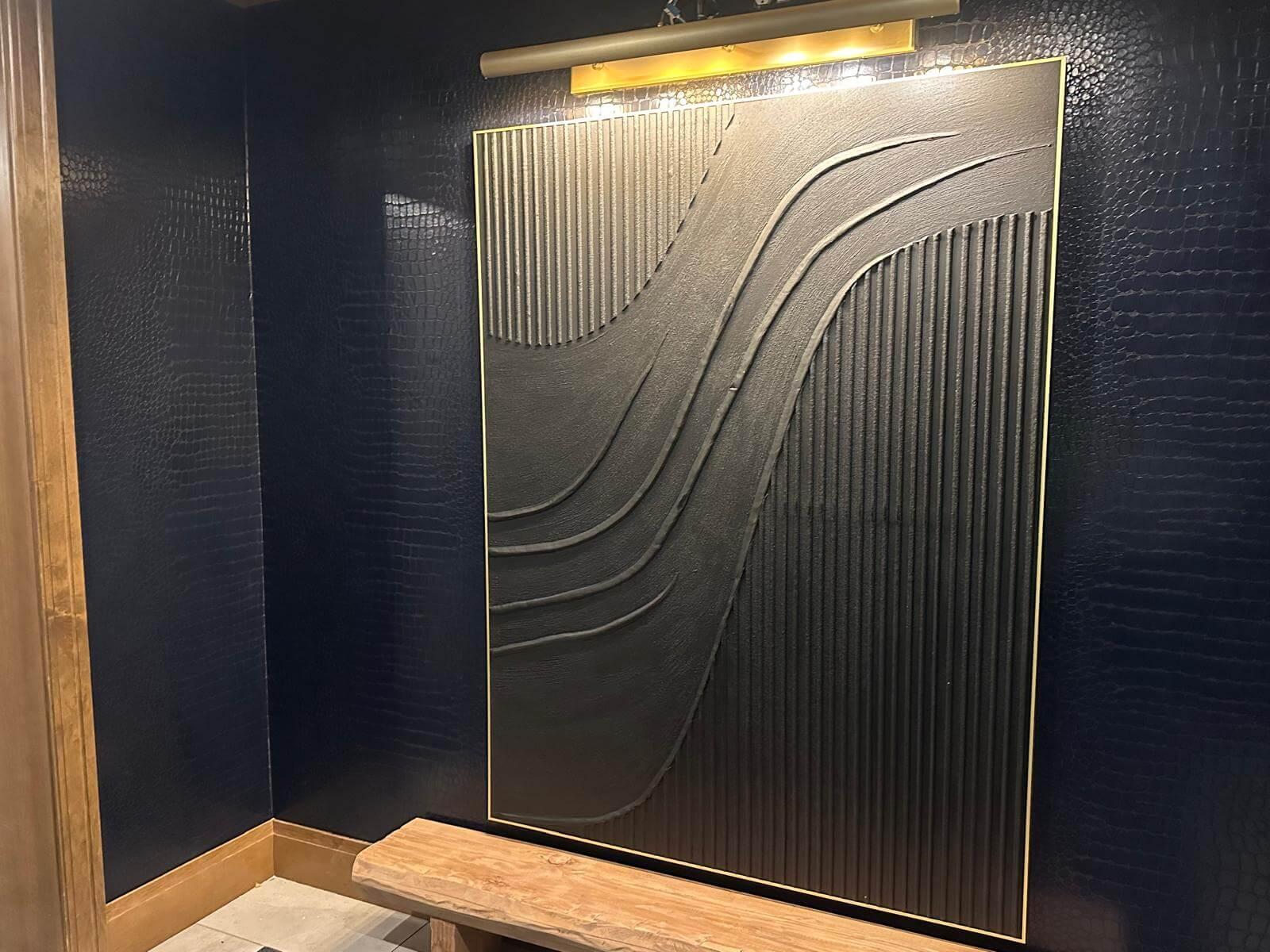 Wallpaper with a snake print installed on a wall behind a large art frame.