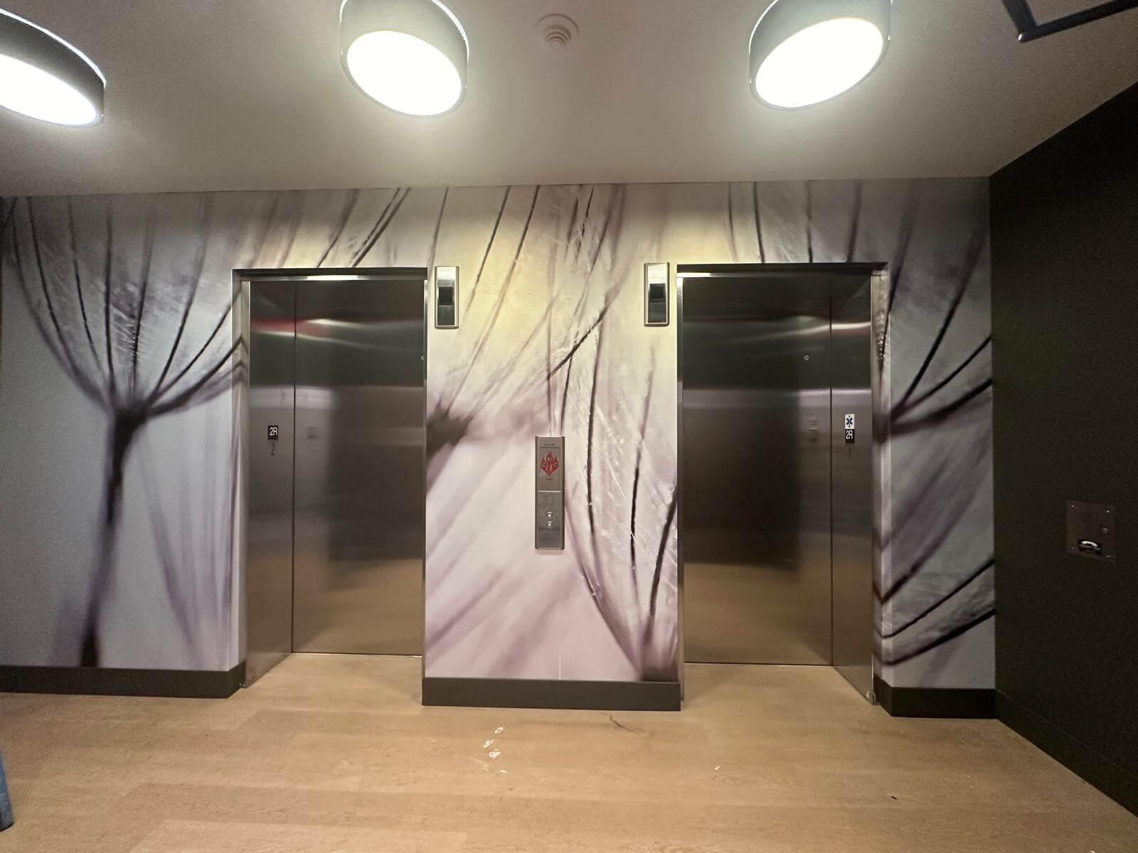 Elevator lobby with large dandelion wallpaper installed around the elevator doors.