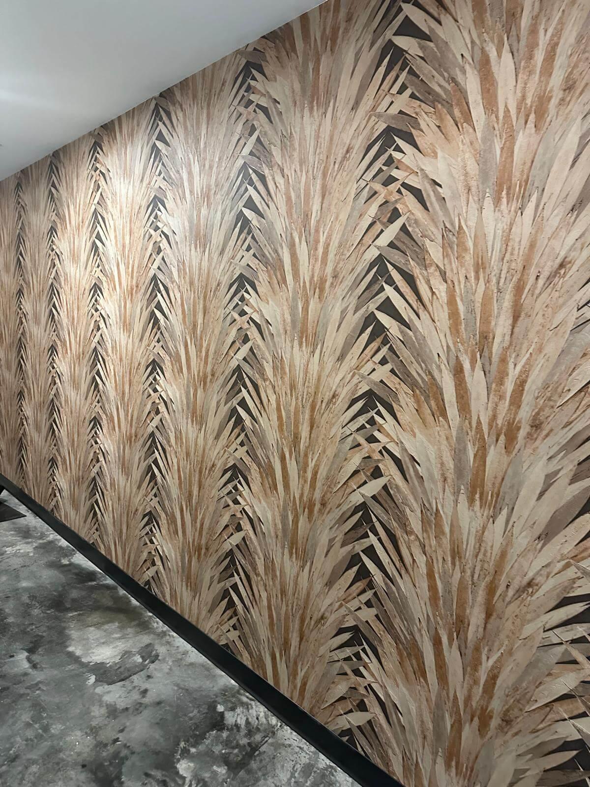 Wall showing wallpaper with feathery upward and overlapping strokes in shades of beige and brown.